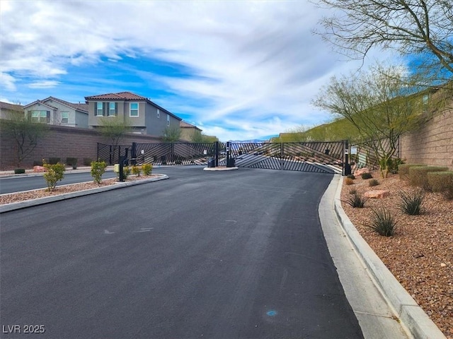 view of road with curbs, a gated entry, a residential view, and a gate