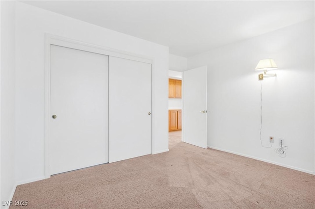 unfurnished bedroom with a closet and light colored carpet