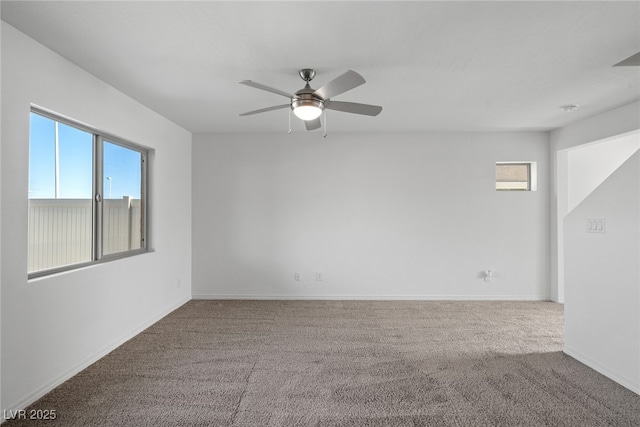 carpeted spare room featuring baseboards and a ceiling fan