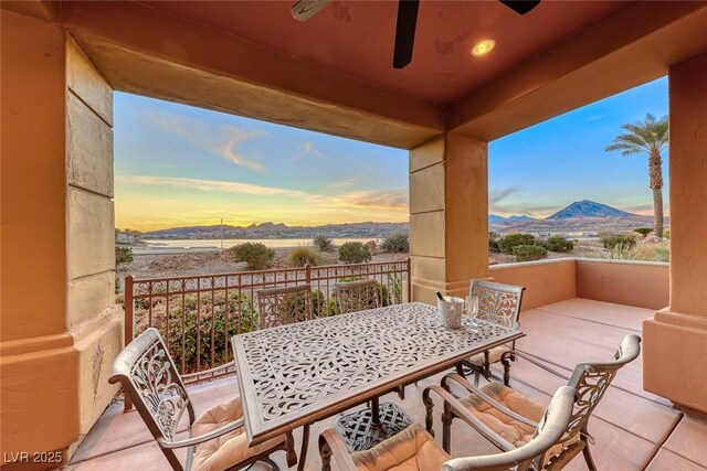 patio terrace at dusk with ceiling fan, outdoor dining area, and a mountain view