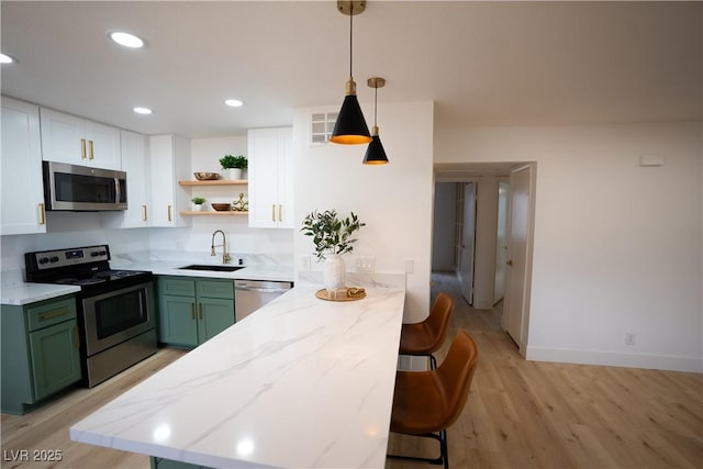 kitchen featuring open shelves, white cabinets, appliances with stainless steel finishes, green cabinets, and a sink