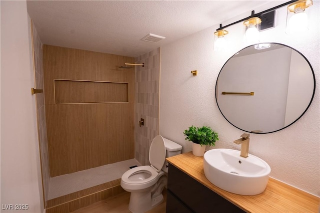 bathroom with visible vents, a textured wall, toilet, a stall shower, and a textured ceiling