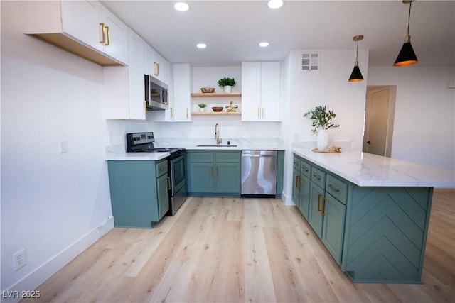 kitchen with a peninsula, a sink, white cabinetry, hanging light fixtures, and appliances with stainless steel finishes