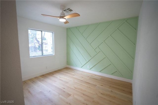 empty room with light wood finished floors, ceiling fan, visible vents, and baseboards