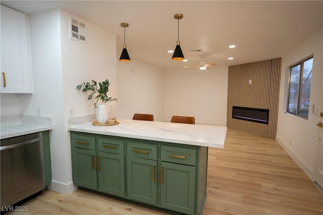 kitchen featuring a peninsula, visible vents, stainless steel dishwasher, light wood-type flooring, and green cabinetry