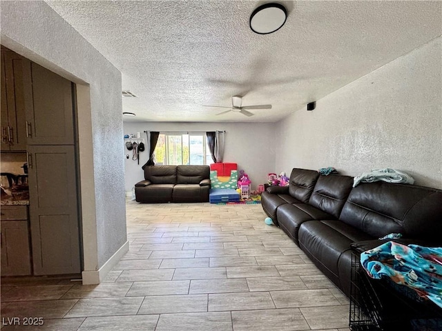 living room featuring a ceiling fan, visible vents, a textured wall, and a textured ceiling