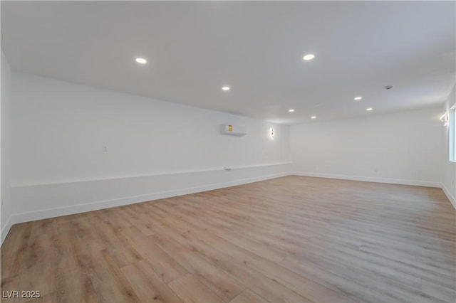 unfurnished room featuring recessed lighting, an AC wall unit, light wood-style flooring, and baseboards