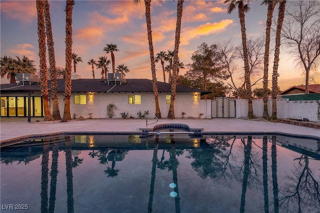 view of swimming pool with a patio, fence, and a pool with connected hot tub