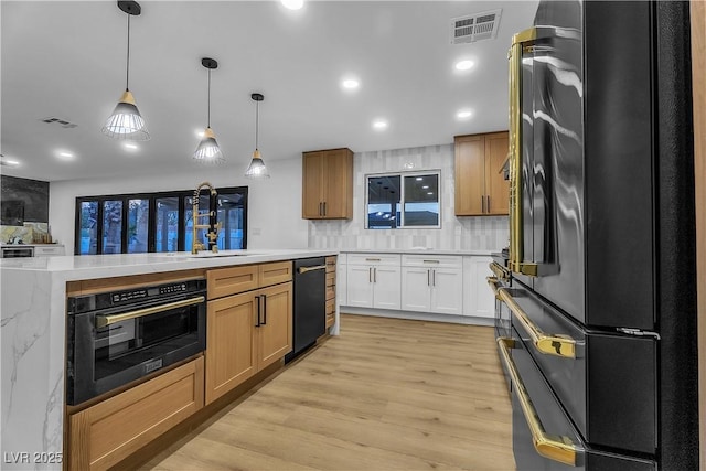 kitchen with decorative light fixtures, light countertops, visible vents, white cabinetry, and black appliances