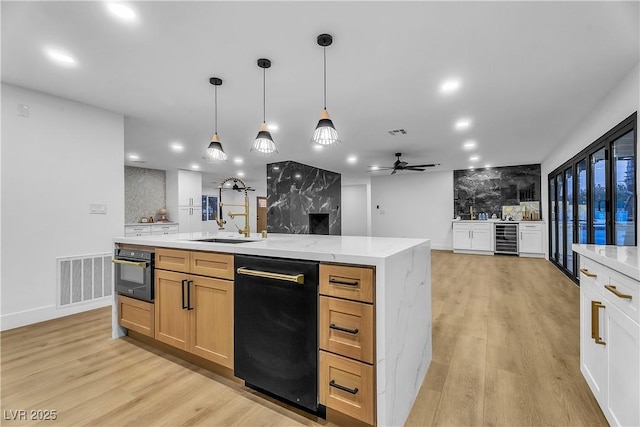 kitchen with a spacious island, wine cooler, light brown cabinetry, pendant lighting, and a sink