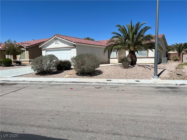 view of front of home with a garage, concrete driveway, a tiled roof, cooling unit, and stucco siding