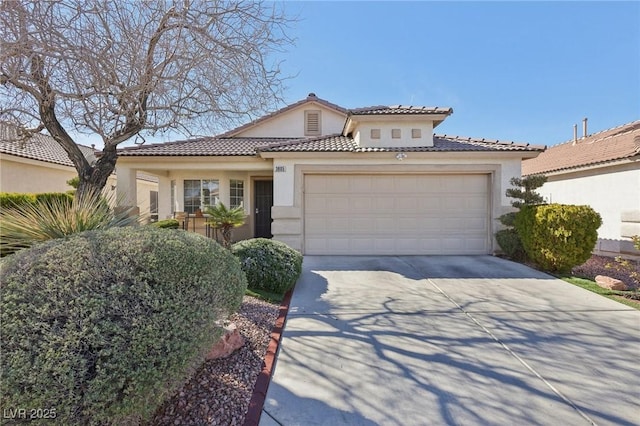 mediterranean / spanish home with a garage, a tiled roof, concrete driveway, and stucco siding