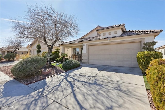 mediterranean / spanish house with a garage, driveway, a tile roof, and stucco siding