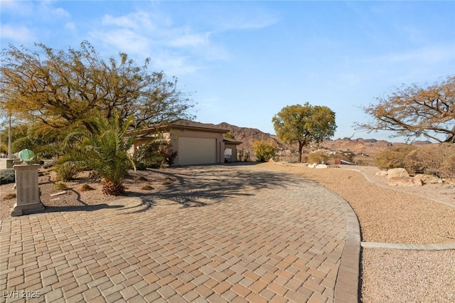 view of front facade with decorative driveway, a mountain view, and an attached garage