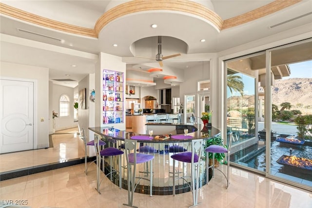 bar with a mountain view, recessed lighting, a ceiling fan, ornamental molding, and wall chimney range hood