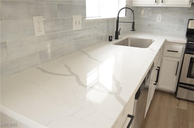 kitchen featuring light stone countertops, decorative backsplash, white cabinets, and a sink