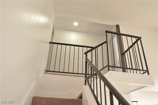 staircase featuring a textured ceiling and recessed lighting