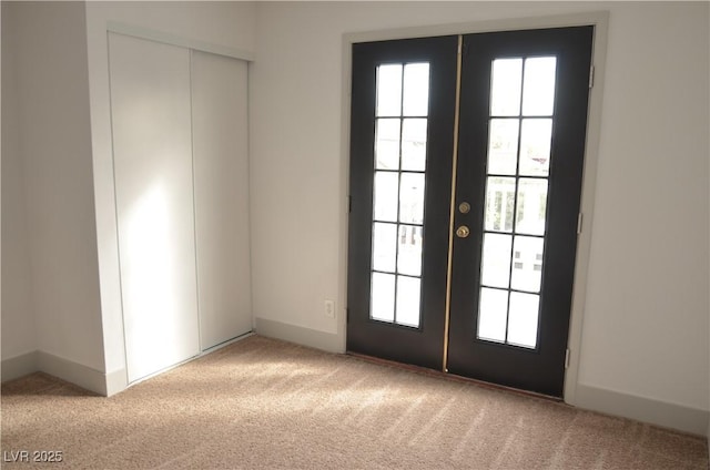 entryway with a wealth of natural light, french doors, light colored carpet, and baseboards