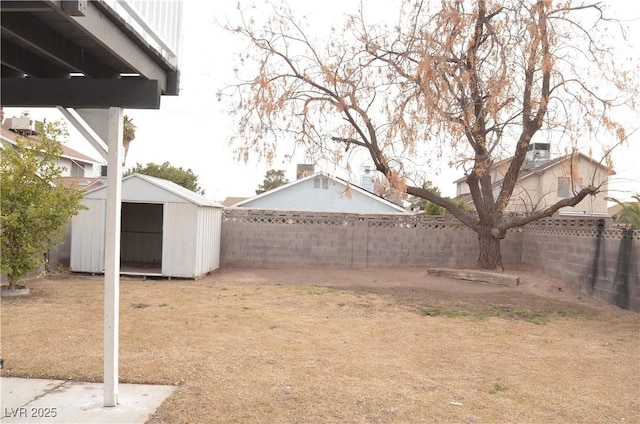 view of yard featuring a shed, a fenced backyard, and an outbuilding