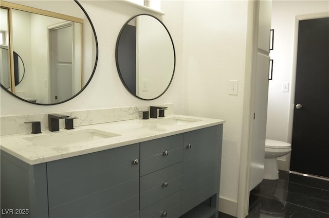 bathroom with a sink, toilet, and double vanity