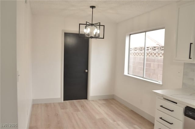 unfurnished dining area featuring light wood finished floors, a wealth of natural light, and baseboards