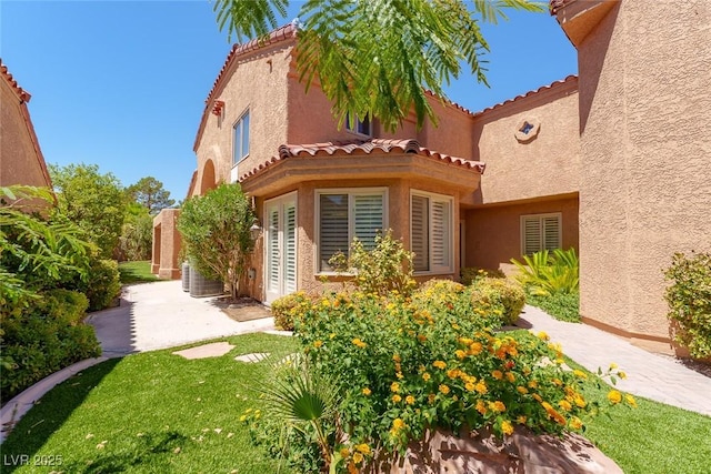 back of property with a tiled roof, a yard, a patio area, and stucco siding