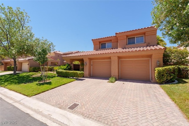 mediterranean / spanish home with decorative driveway, a front yard, a tile roof, and stucco siding