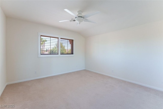 spare room featuring light carpet, lofted ceiling, a ceiling fan, and baseboards