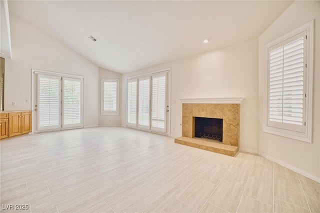 unfurnished living room featuring light wood-type flooring, baseboards, vaulted ceiling, and a tiled fireplace