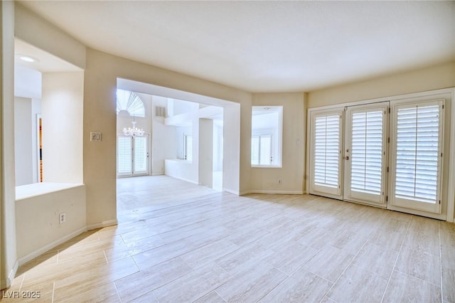 empty room with baseboards, visible vents, and an inviting chandelier