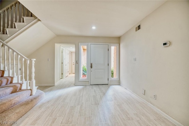 foyer entrance with stairway, wood finished floors, visible vents, and baseboards