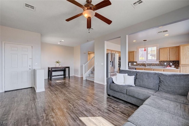 living room featuring dark wood-type flooring, visible vents, and stairs