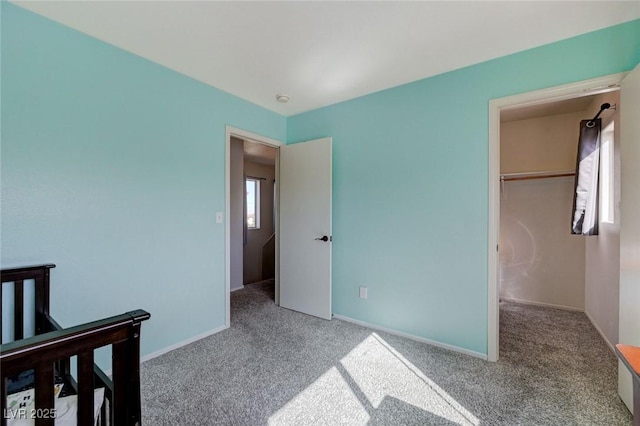 bedroom with light carpet, a spacious closet, and baseboards