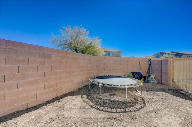 view of yard with a trampoline and a fenced backyard