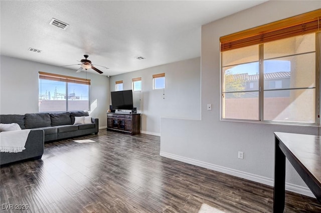 living room featuring visible vents, dark wood finished floors, baseboards, and ceiling fan