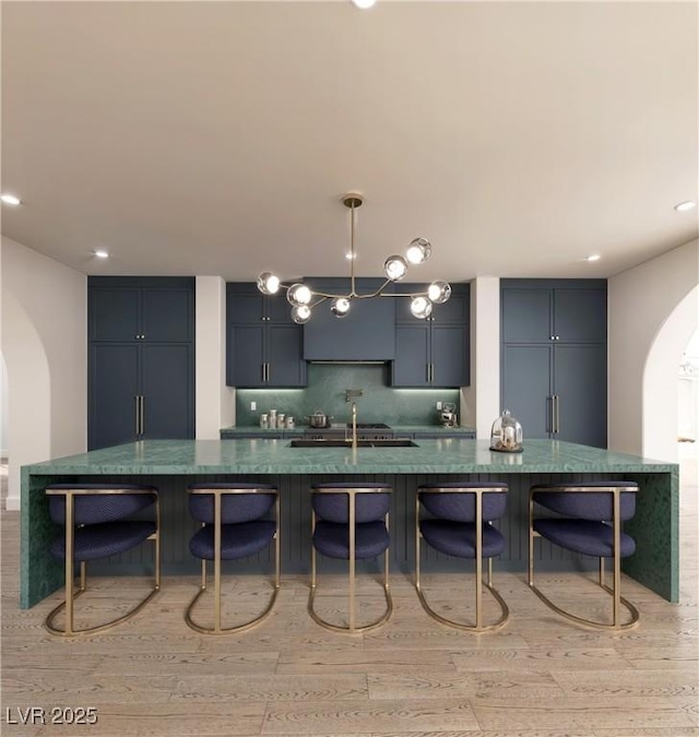 kitchen featuring arched walkways, dark countertops, light wood-style flooring, and decorative backsplash