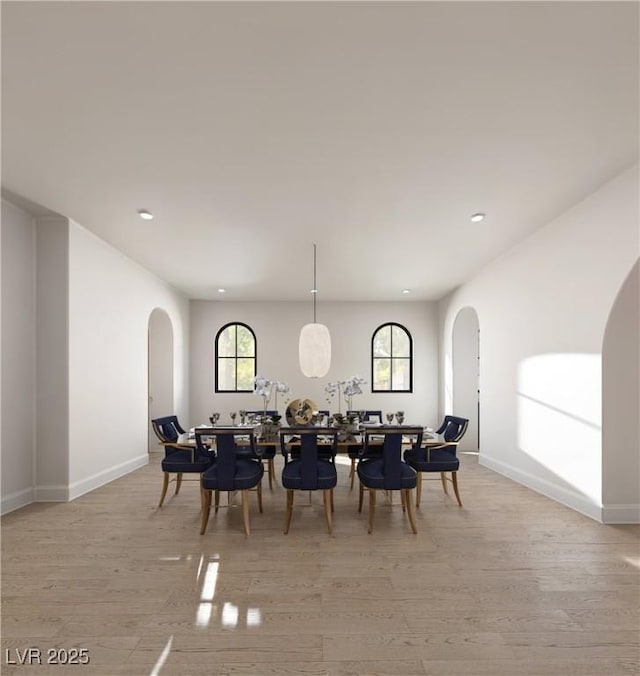 dining space with light wood-style floors, arched walkways, baseboards, and recessed lighting