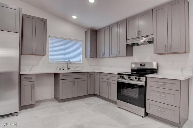 kitchen featuring gray cabinetry, under cabinet range hood, stainless steel appliances, a sink, and light countertops