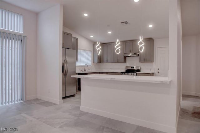 kitchen featuring visible vents, stainless steel appliances, under cabinet range hood, pendant lighting, and a sink