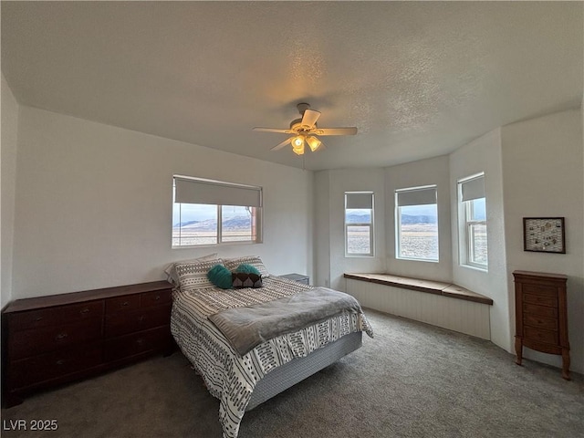 bedroom with a ceiling fan, dark carpet, and a textured ceiling