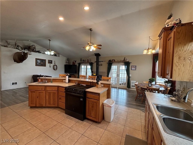 kitchen with a sink, black range with electric stovetop, open floor plan, and light tile patterned floors