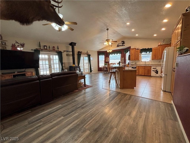 kitchen with light wood finished floors, open floor plan, a breakfast bar area, freestanding refrigerator, and a wood stove