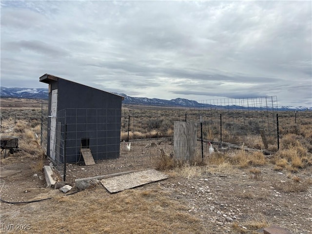 exterior space featuring a mountain view, an outdoor structure, and fence