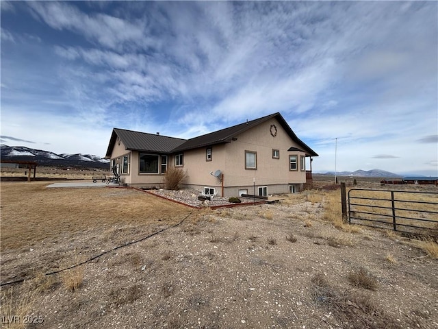 back of house with metal roof, a mountain view, and fence