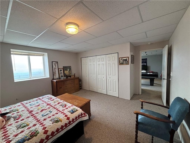 carpeted bedroom with a paneled ceiling and a closet