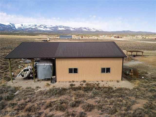 exterior space featuring an outbuilding, a detached garage, a mountain view, metal roof, and a carport
