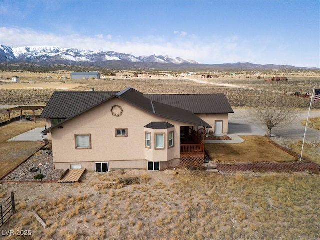 back of property with stucco siding, a mountain view, and metal roof