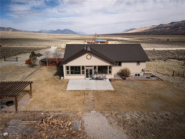 back of house featuring a mountain view, a patio, metal roof, and fence