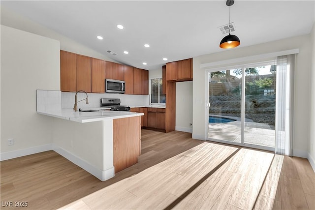 kitchen with visible vents, appliances with stainless steel finishes, hanging light fixtures, light countertops, and a sink