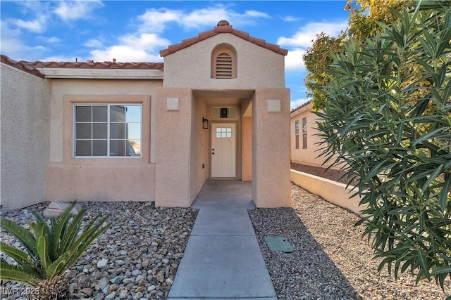 property entrance with a tile roof and stucco siding